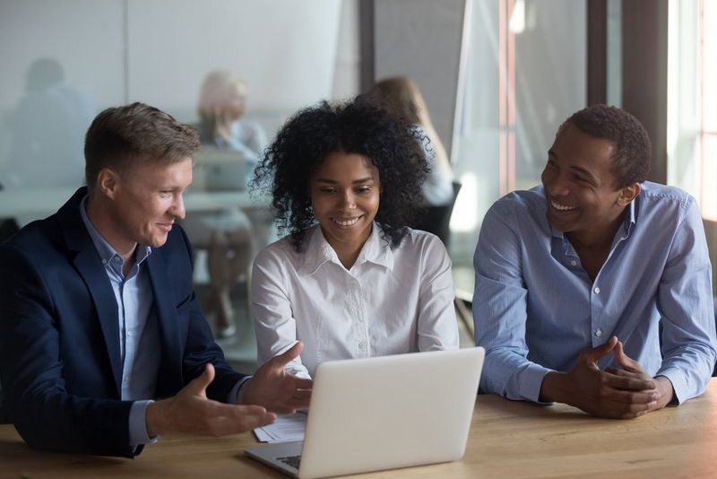 three people looking at a laptop