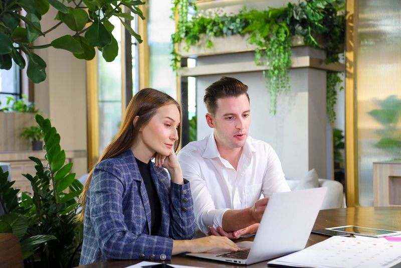 two work professionals working on laptops