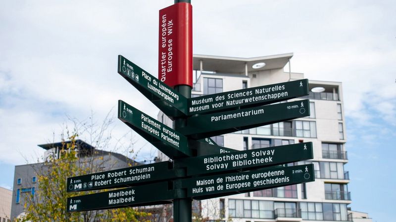 Signpost at the Crossroads in Brussels, in the middle of the European Quarter, with arrows leading to the EU Parliament, to Place du Luxembourg, Place Robert Schuman, the Parlamentarium and many more
