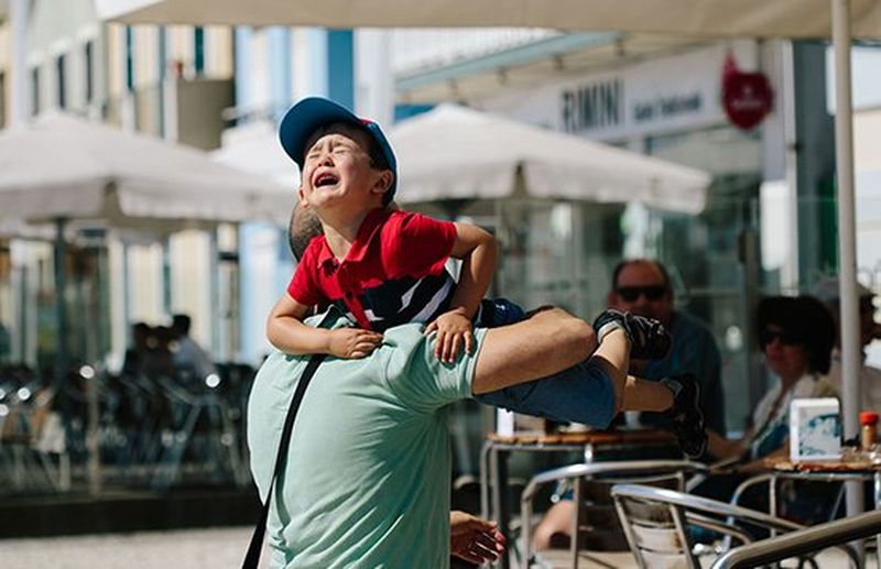crying child carried by parent