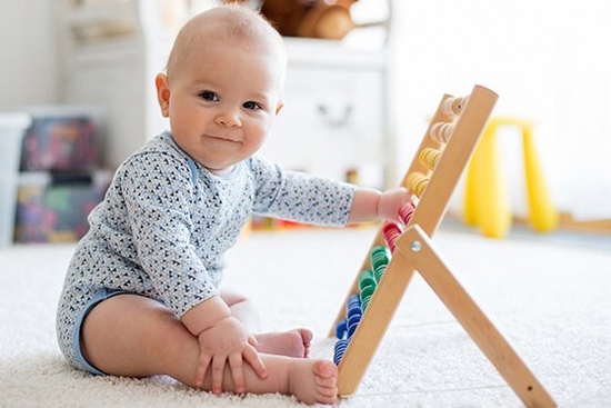 A baby plays with an abacus.