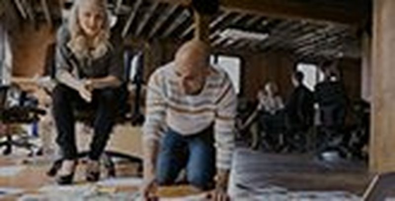 Man kneeling on floor looking at prints