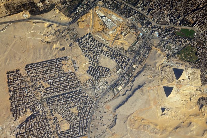 A satellite view of view of the Giza Necropolis, showing the Great Pyramids and surrounding urban areas.