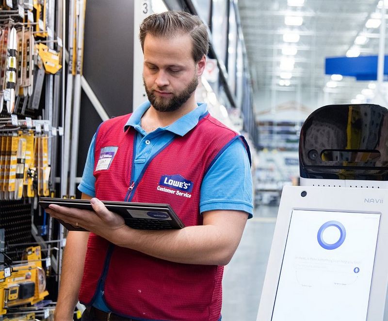 Retail assistant standing with robot checking inventory.