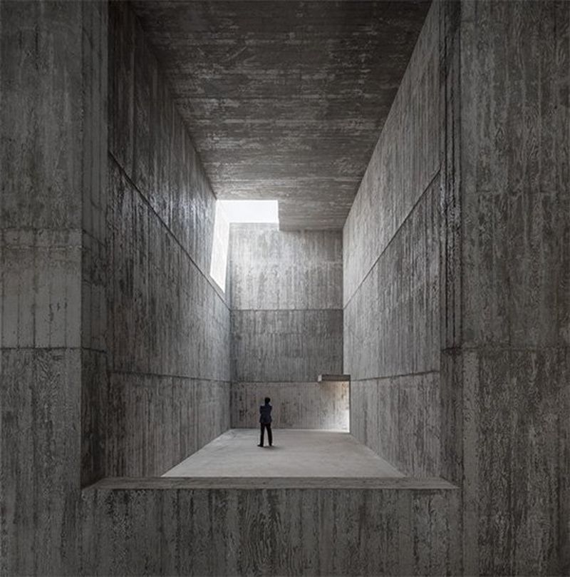 A person appears small in a huge polished concrete room with thick walls. Photo by Fernando Guerra with a Canon TS-E 17mm f/4L lens.