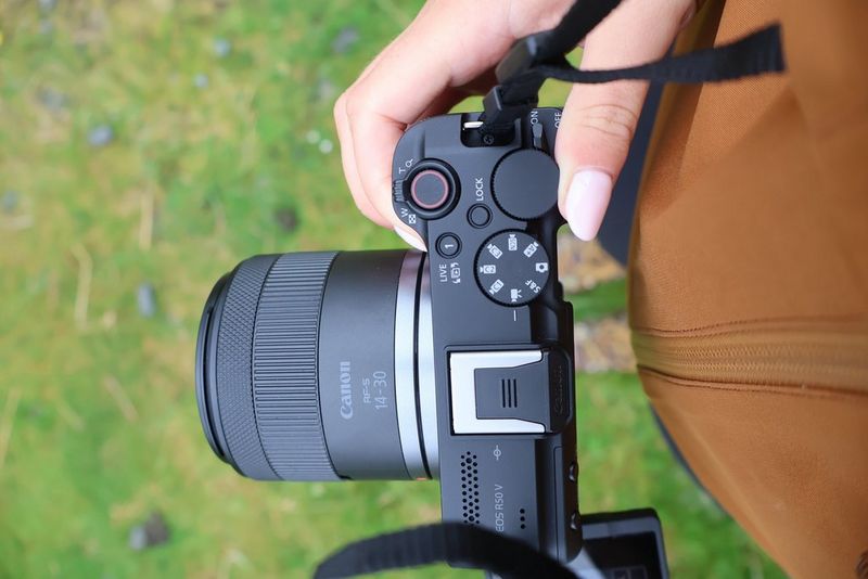 Vlogger Niamh Mackinnon’s hand holds a Canon EOS R50 V, showing the top controls, designed for content creators.