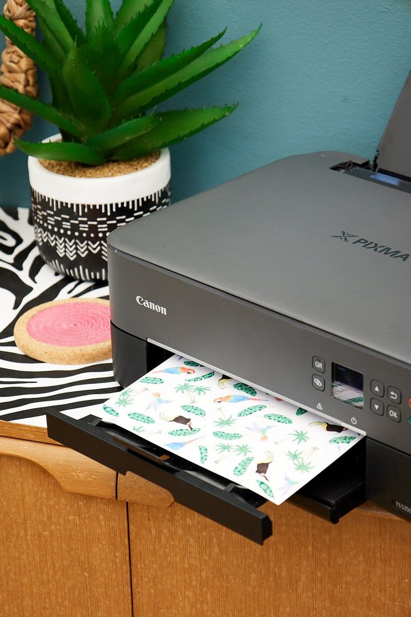 Een vel papier waarop tropische vogels en bladeren zijn geprint komt uit een Canon PIXMA-printer.