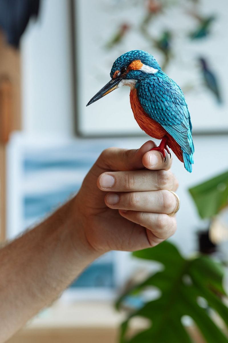 Человек держит в руке цветную 3D-модель зимородка, изготовленную из бумаги Canon по шаблону, который был загружен с веб-сайта Canon Creative Park.