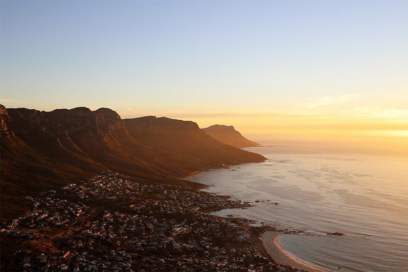 A view looking out over a seaside town at sunset, with steep hills behind it. Photo taken on a Canon EOS RP