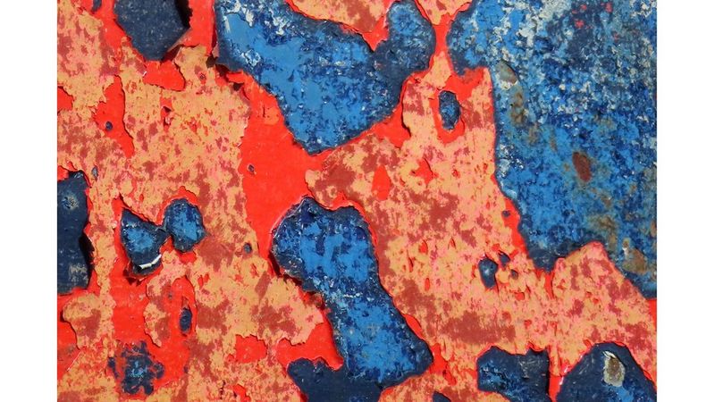 A close-up of the boat’s hull shows flaky red and blue paint with a metallic texture.