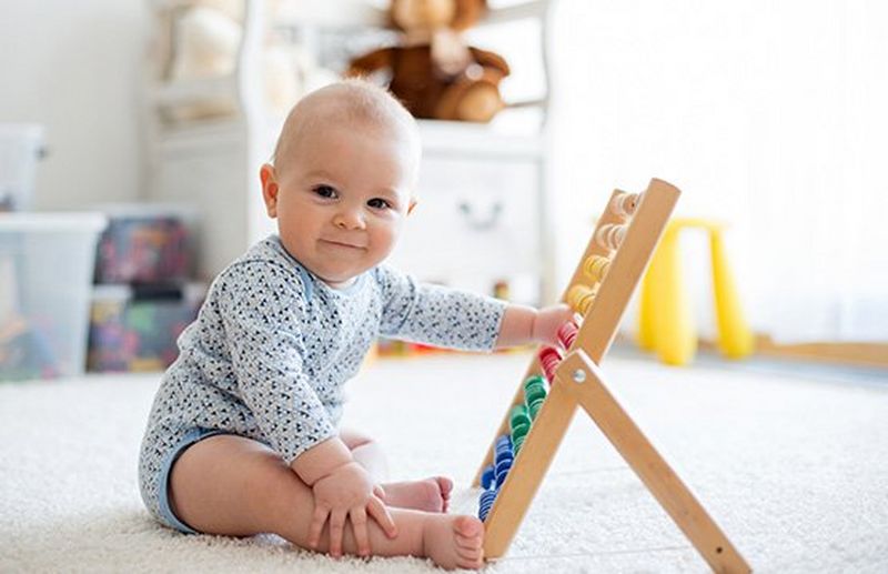A baby plays with an abacus.