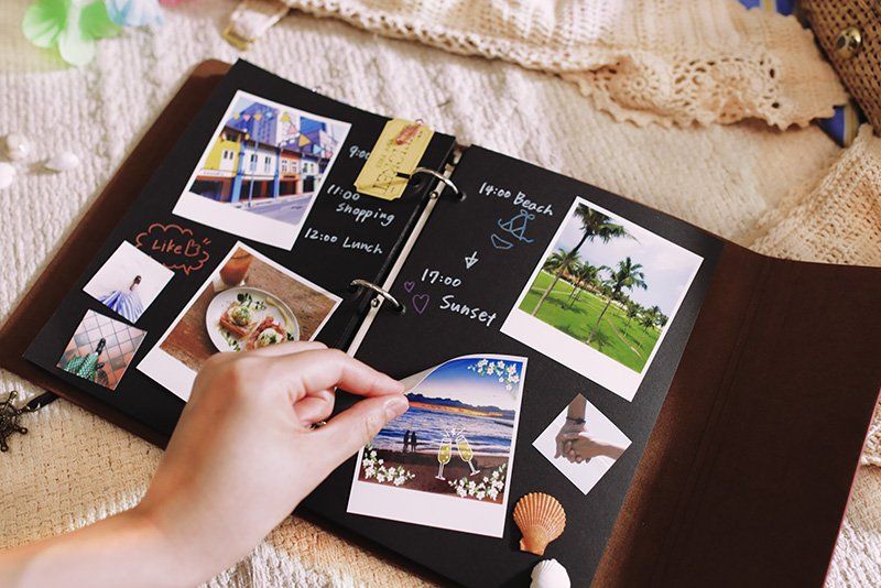 A woman’s hand placing a photograph of a couple at the beach into a holiday