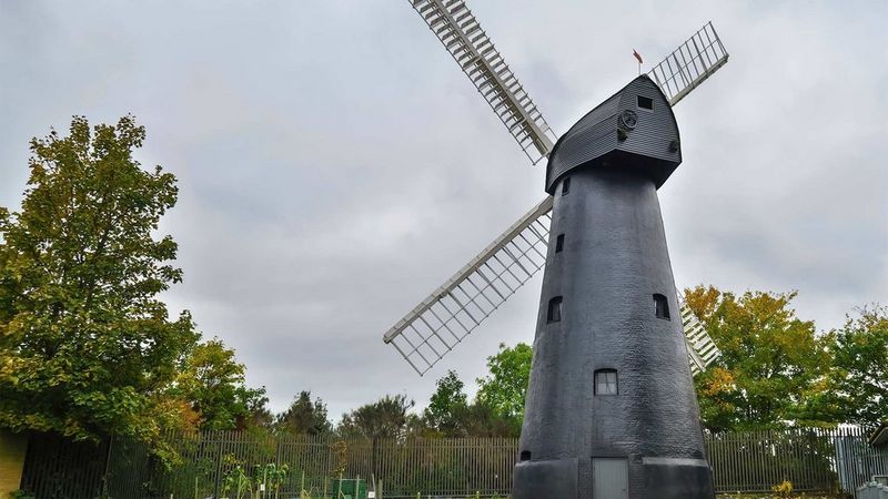 A windmill against a green countryside background on a cloudy day