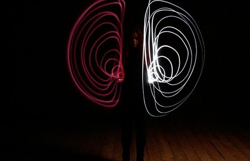 Two spirals of light, one pink and one white, against a black background.