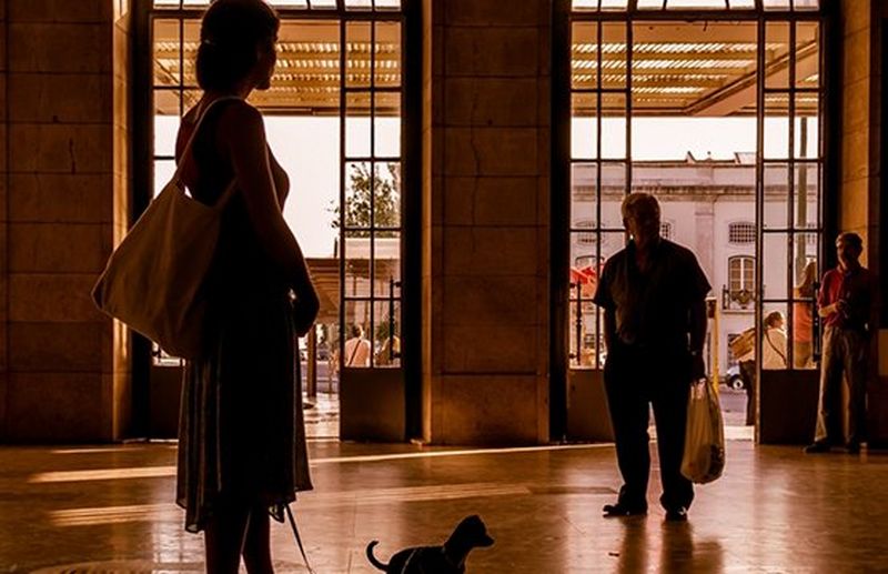 A sepia-toned candid shot of people inside a station building, silhouetted.