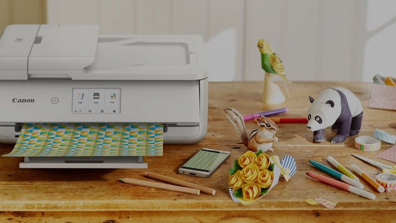 Printer on table next to pens, pencils and desk toys.