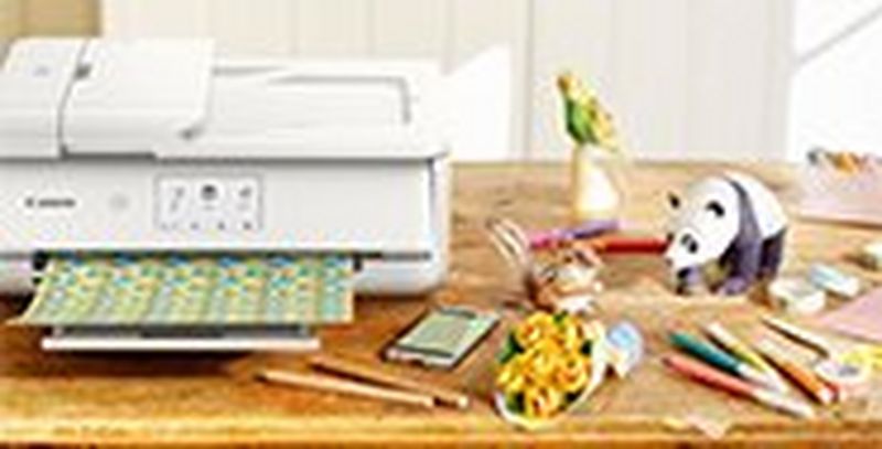 A printer on a table next to pens, pencils and desk toys. 