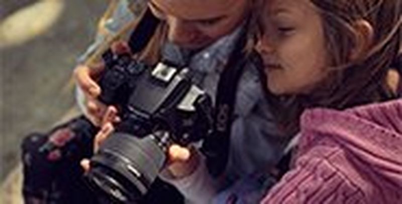 A woman and girl look at the back of a Canon EOS 250D