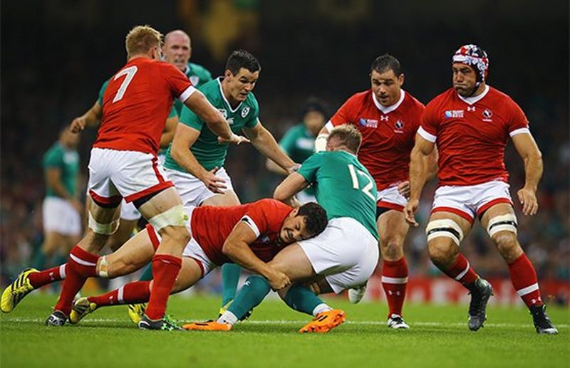 A Canadian player tackles an Irish player during a rugby match. Photo by Richard Heathcote.