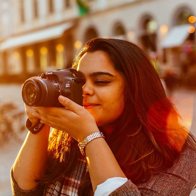  A woman looks through her Canon camera at sunset.