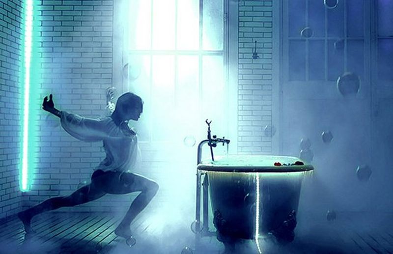 A dancer poses next to a bath tub.