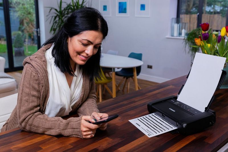 A woman working from home prints on a Canon PIXMA TR150 from a smartphone.