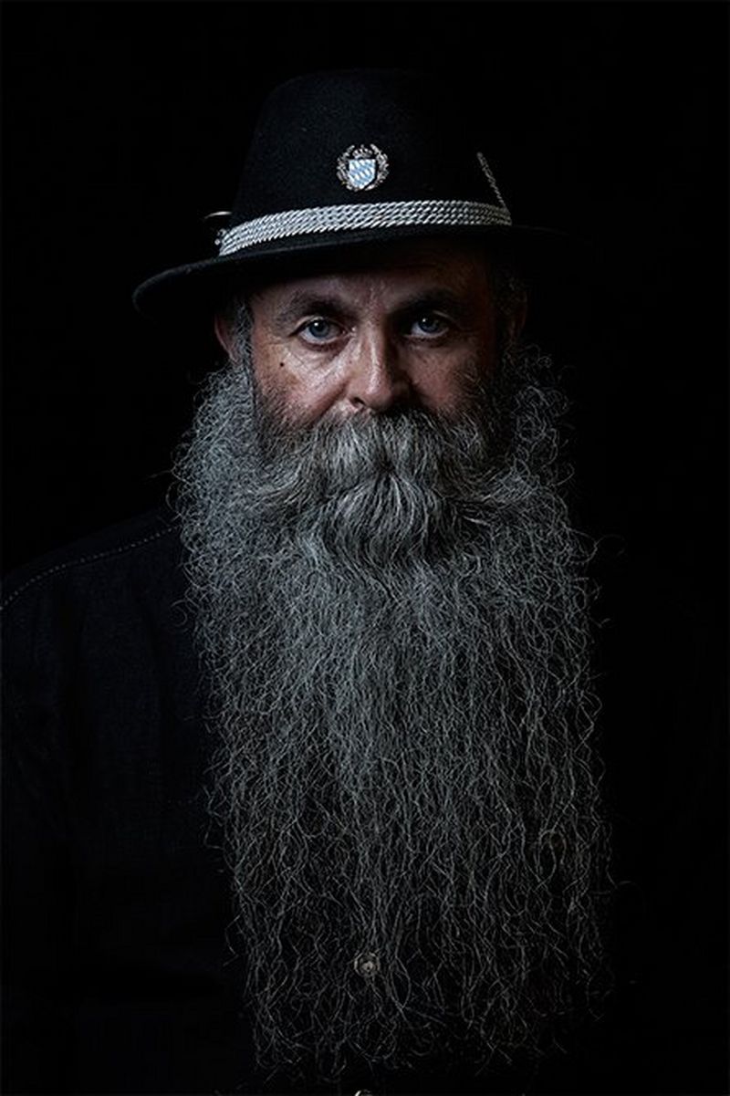 A man with long grey beard wearing a dark cap with a blue Bavarian crest