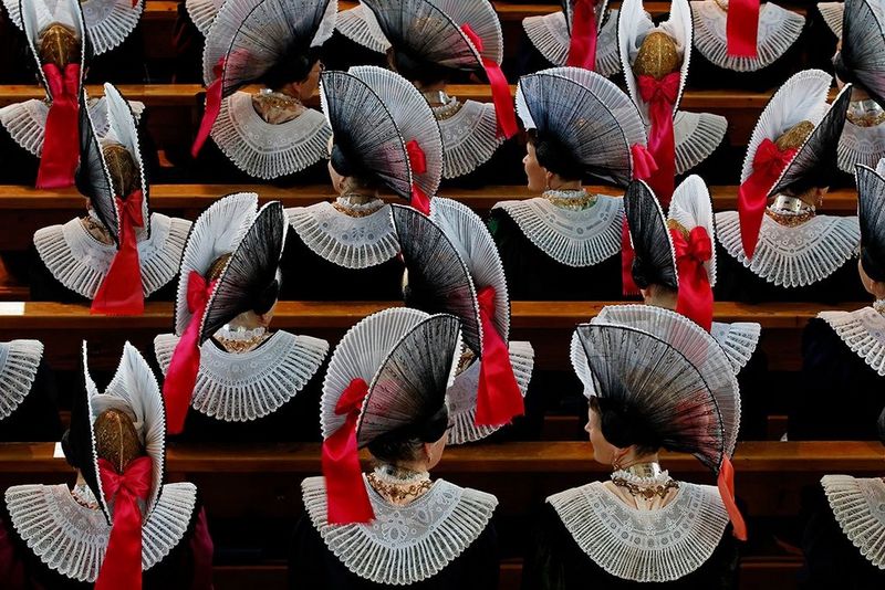 View from above of religious women in ornate costumes, sitting in church pews.