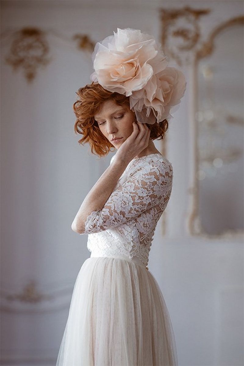A bride wearing large flowers in her hair looks down dreamily. Photo by Félicia Sisco with a Canon RF 85mm F1.2L USM lens.