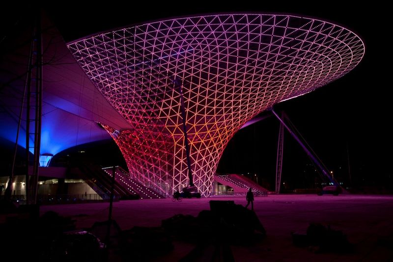 An example of modern architecture in China, Shanghai's Expo Axis lit up with pink light in geometric lines.