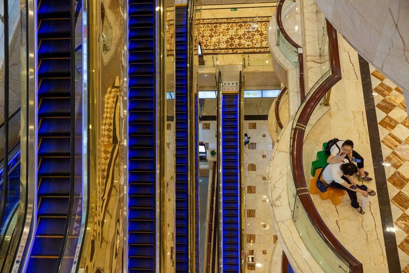 A shot taken looking down inside the New Century Global Mall in Chengdu, showing escalators lit up with blue lights. 