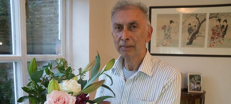 Photographer Chris Steele-Perkins stands in a room at home beside some flowers.