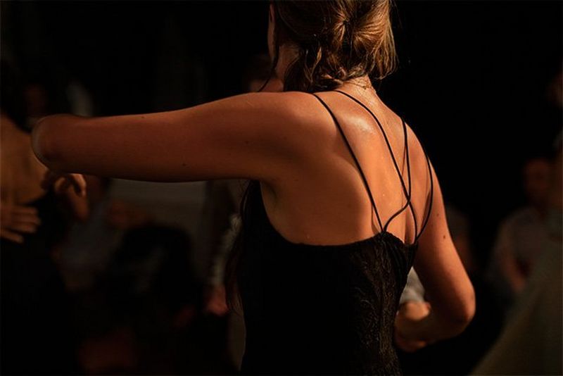 A close-up of a woman’s back, her skin glistening with perspiration.