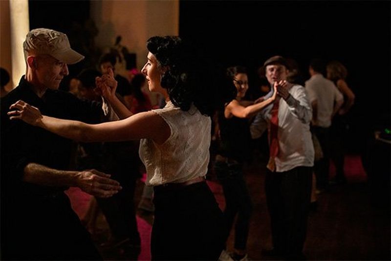Couples in black and white hold each other as they dance.