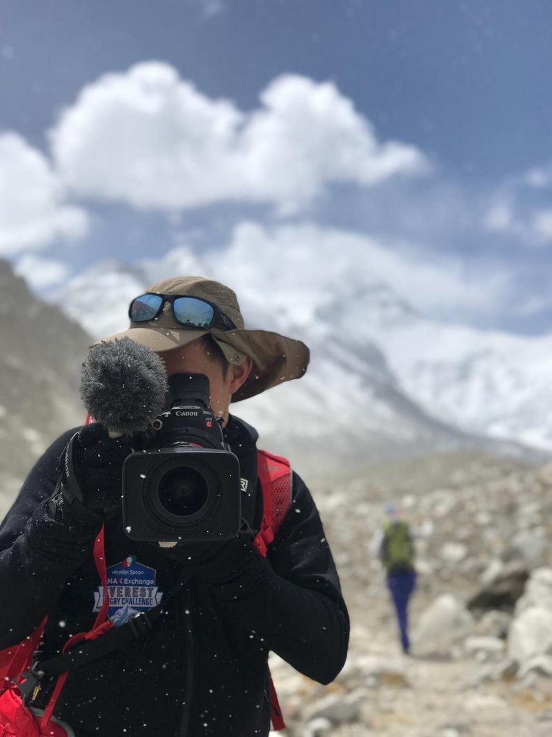 Filmmaker Sam Tongue holds a Canon EOS C200 video camera in front of Mount Everest.