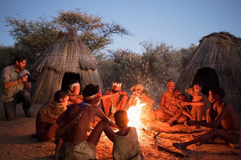 Brent Stirton photographs Namibian tribespeople by the fire, as Spencer MacDonald films him using a Canon EOS C200.