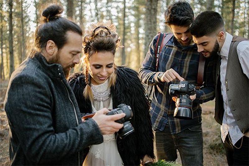 Photographers of Factoria182 show bride and groom photos on their camera screens.