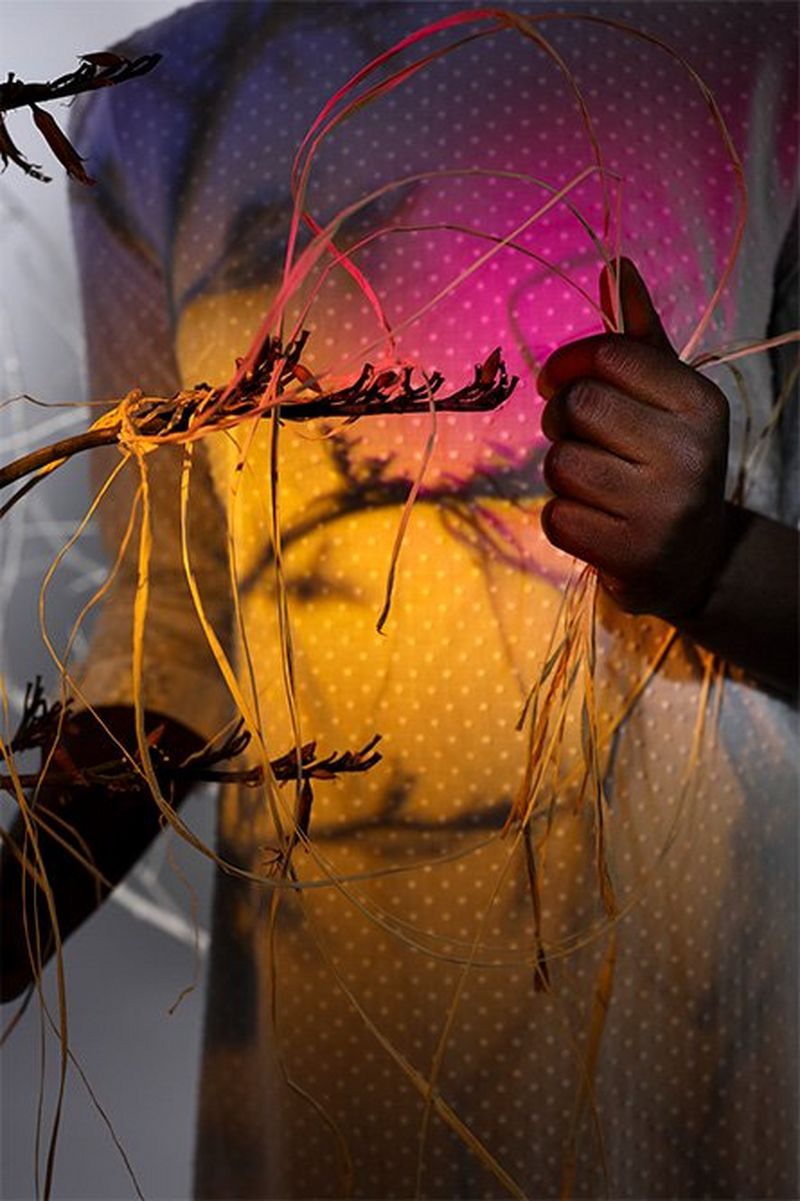 An abstract portrait with the head cropped out of shot, and coloured gels projecting pink and yellow light onto the dress of a model.