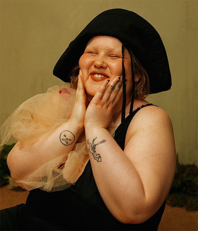 A bunch of pale pink flowers, starting to wilt, lie on a grey sack cloth.