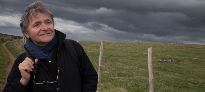 Jean Gaumy with his kitbag over his shoulder standing in a windswept field
