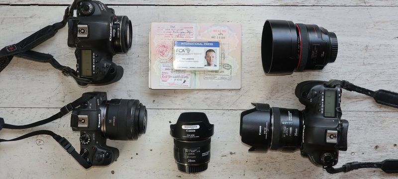 The contents of Kim Ludbrrok’s kitbag – three Canon cameras and 4 lenses – laid out on a table.