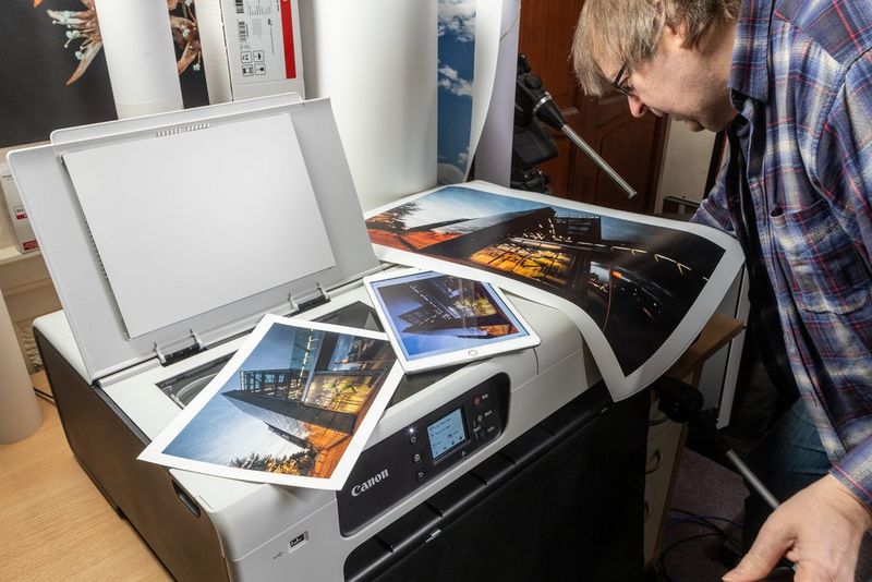 Professioneel fotograaf Keith Cooper bestudeert een grote print die bovenop een grootformaat printer van Canon ligt. Naast de print ligt een tablet met daarop dezelfde afbeelding en een kleinere print.