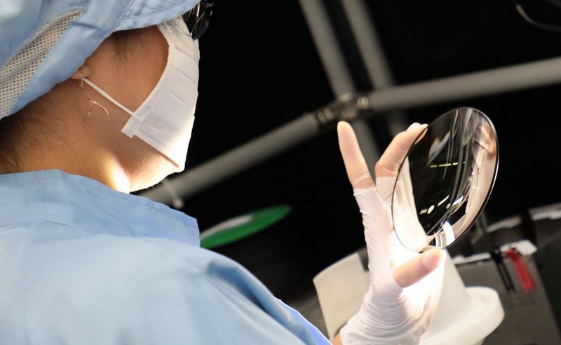 An engineer centres the glass on a machine, ready to be ground into a lens.