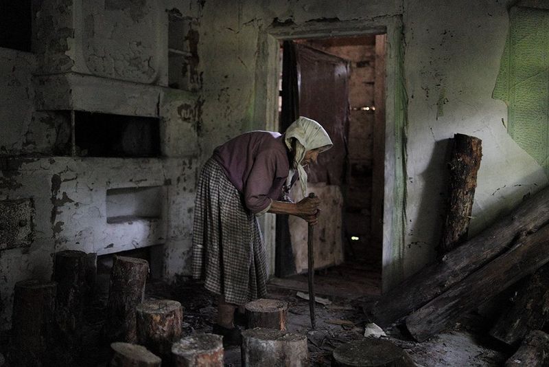 A hunched woman in a derelict house in Chernobyl.