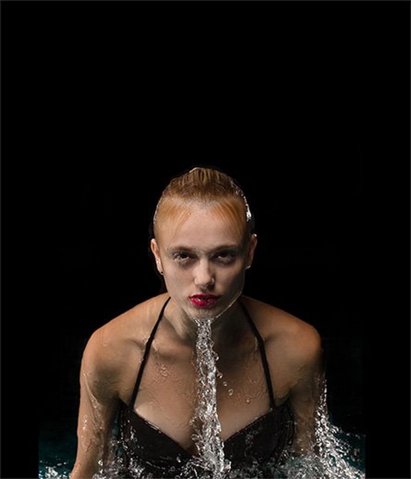 A woman coming up from the water with a black background.