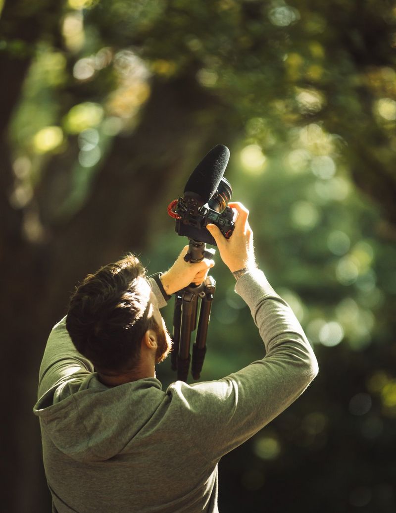 Stefan Michalak holding his kit up to film the trees in the park. 
