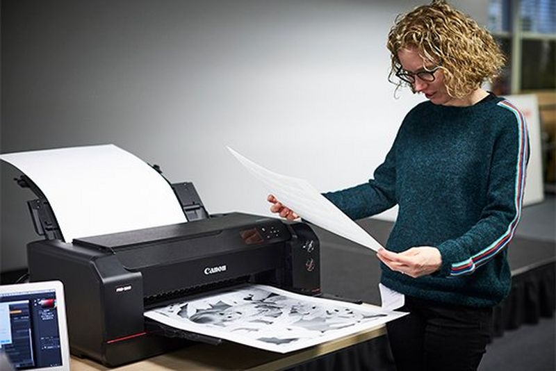 Helen Bartlett stands next to a Canon imagePROGRAF PRO-1000 printer looking at an A2 black and white photo print.
