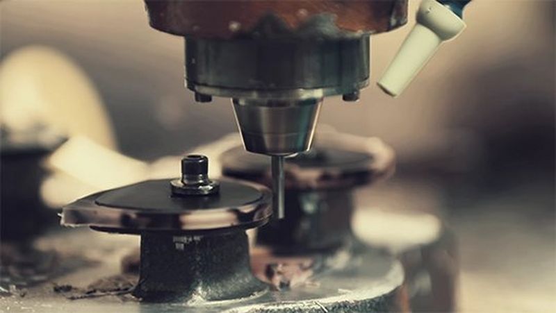 A close-up of a router shaping the eyepieces of a pair of glasses. A still from a video by Quentin Caffier.