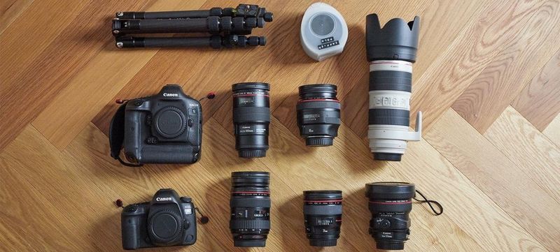 Quentin Caffier&#39;s photo kit on a wooden floor, including an EOS 5D Mark IV plus several lenses.