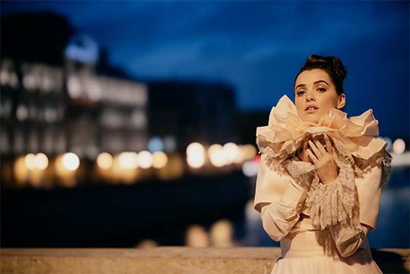 A night-time bridal portrait, with soft-edged bokeh on a row of lights in the background. Photography by Félicia Sisco.